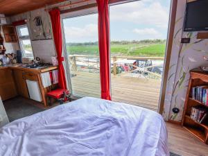 a bedroom with a bed and a balcony with a view at Riverside Cabin in Peterborough