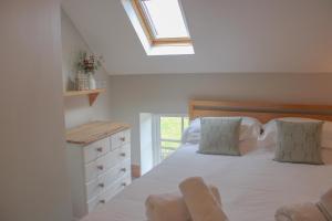 a bedroom with a white bed with a skylight at School House Cottage in Buxton