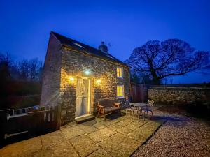 a small stone house with a table and chairs at School House Cottage in Buxton