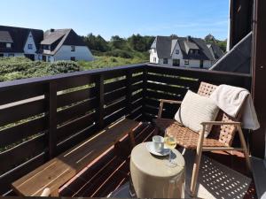 a balcony with a chair and a table with a glass of wine at Ferienwohnung-Sturmfri-e-se in Hörnum