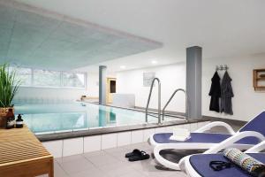 a large swimming pool with chairs and a table at Ferienwohnung-Sturmfri-e-se in Hörnum