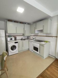 a kitchen with white cabinets and a washer and dryer at El Descanso del Cares in Arenas de Cabrales