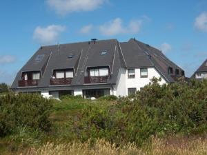 a white house with a black roof on a hill at RUeM-HART-I-Whg-2 in Hörnum