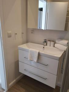 a white bathroom with a sink and a mirror at RUeM-HART-I-Whg-2 in Hörnum +6 photos