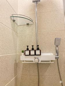 a shower with three bottles on a shelf in a bathroom at 더스테이365 스탠다드 in Seoul +1 photo