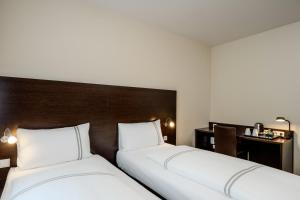 two beds in a hotel room with a desk at Premier Inn Berlin City Spittelmarkt in Berlin
