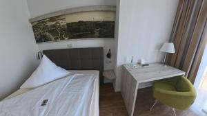 a bedroom with a bed and a desk with a green chair at Hotel Residence in Bad Segeberg
