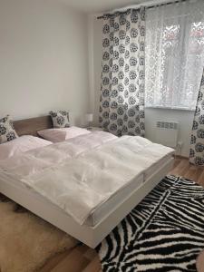 a white bed in a bedroom with a rug at Apartman Pod Vysokymi Tatrami in Nová Lesná