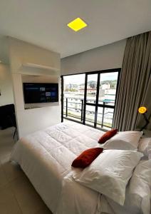 a bedroom with a large bed with a large window at RCM Vilas - Apartamento 306 in Joinville