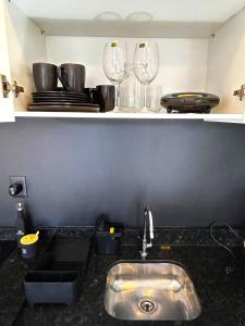 a kitchen counter with a sink and two wine glasses at RCM Vilas - Apartamento 306 in Joinville +12 photos