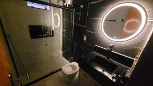 a bathroom with a toilet and a round mirror at Casa Tecnoshow 2026 in Rio Verde +2 photos