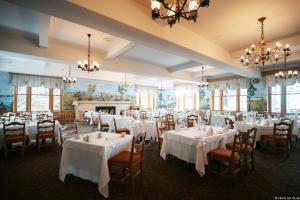 ein Esszimmer mit weißen Tischen und Stühlen und einem Kamin in der Unterkunft Hotel Tadoussac in Tadoussac
