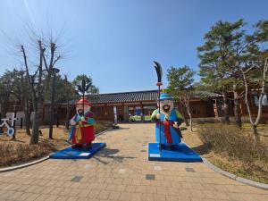 two toy figurines are on display in a park at 여유스테이 in Suwŏn-yŏk