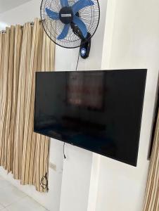 a flat screen tv hanging on a wall with a fan at Private Room at MA Compound in Concepcion