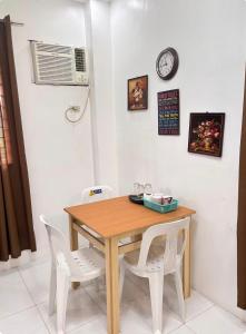 a dining room table with two white chairs and a clock at Private Room at MA Compound in Concepcion