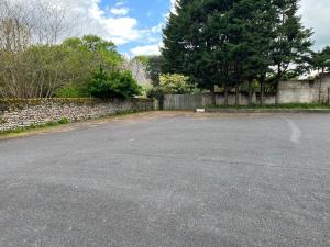 an empty parking lot in front of a stone wall at Les gîtes de Mazélise in Mazerolles