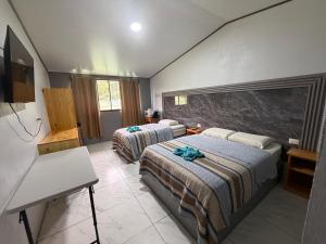 a hotel room with two beds and a desk at Hotel Uran in Rivas