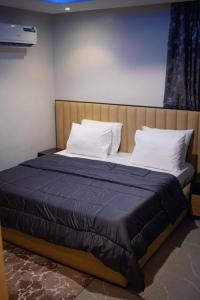 a bed with a blue blanket and white pillows at Emerald Apartments in Lagos