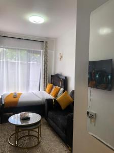 a room with a bed and a couch and a table at Thesh Home at Tsavo Sunset 2 ,Thindigua Kiambu Road in Kiambu