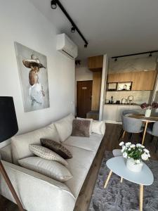 a living room with a white couch and a kitchen at SPV Rentals Premium Apartament Wołoska 3 in Warsaw