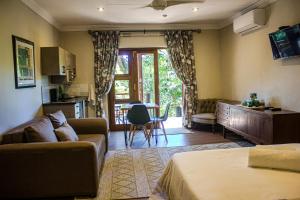 a living room with a couch and a table and a kitchen at Kruger's Rest Guest House in Hazyview