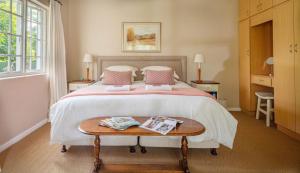 a bedroom with a large bed with a wooden table at Lloyd Road Cottage in Port Elizabeth