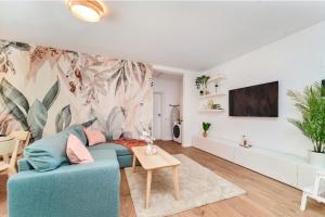 a living room with a blue couch and a tv at Matcha Garden apartment in Dumbrăviţa