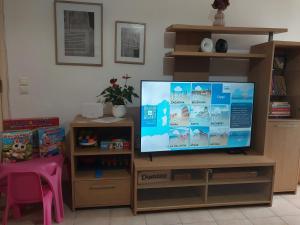 a flat screen tv sitting on a wooden entertainment center at Olive Harmony House in Ariokhórion
