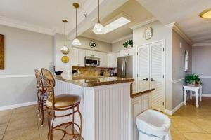 a kitchen with white cabinets and a bar with chairs at Beachfront Condo with Balcony Pools and Gym in Destin +29 photos
