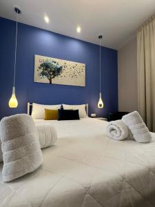 a bedroom with a large white bed with a blue wall at IRIS Boutique Rooms in Korinthos