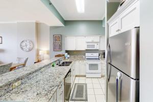 a kitchen with white cabinets and a stainless steel refrigerator at Gulf-Front Condo with Pools and Gym in Destin +29 photos