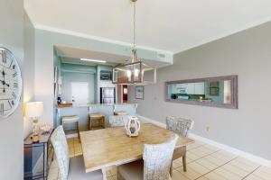 a dining room and kitchen with a wooden table and chairs at Gulf-Front Condo with Pools and Gym in Destin