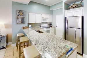 a kitchen with a counter top and a refrigerator at Gulf-Front Condo with Pools and Gym in Destin