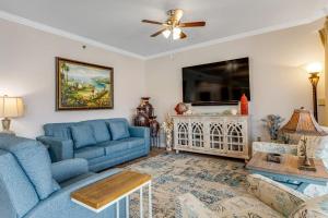 a living room with a blue couch and a tv at Relaxing Waterfront Condo with Pools & Gym Access in Destin