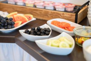 a buffet with bowls of fruits and vegetables on a table at Lexow - Hotel an de Havenkant in Tönning