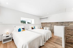 two beds in a bedroom with a stone wall at GuestReady - Quinta da Devesa in Vila Nova de Gaia