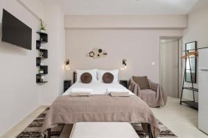 a white bedroom with a large bed and a chair at Katerina's Sunset Apartment in Episkopianá