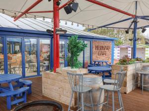 a patio with blue tables and chairs and windows at Winchester - 244 in Rhyl