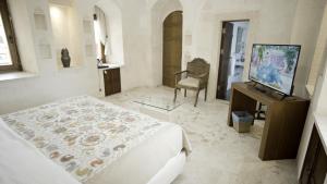 a bedroom with a bed and a tv and a chair at Kasr-i Nehroz Hotel in Midyat