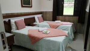 two beds in a room with pink blankets on them at Hotel Colonial in Piraí