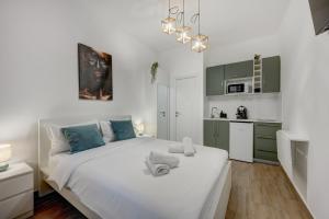 a white bedroom with a large bed and a kitchen at RHUM B07 - Old Town Courtyard in Bucharest