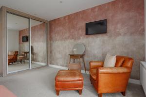 a living room with a chair and a television on a wall at The Laurels by Grandeur Property in Poole