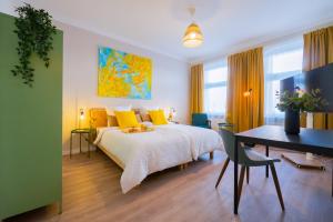 a bedroom with a bed with yellow pillows and a desk at BetterBeds Wilhelm City in Brandenburg an der Havel