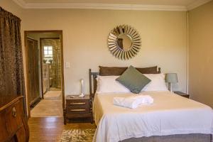 a bedroom with a bed with a mirror on the wall at Kruger's Rest Guest House in Hazyview