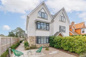 a white house with black windows and chairs at The Laurels by Grandeur Property in Poole