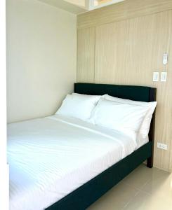 a bed with white sheets and pillows in a room at Modern Stays Makati Pool View Jazz Residences in Manila