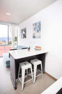 a kitchen with a large white table and two stools at Casa Irazú in Cartago
