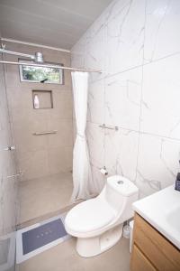 a white bathroom with a toilet and a shower at Casa Irazú in Cartago