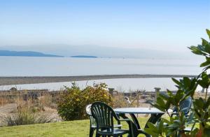 a table and chairs sitting next to the ocean at Beachfront King Bed Studio Suite in Qualicum Beach +18 photos