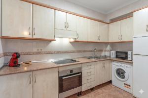 a kitchen with white cabinets and a washer and dryer at Casa Marbella in Fuengirola